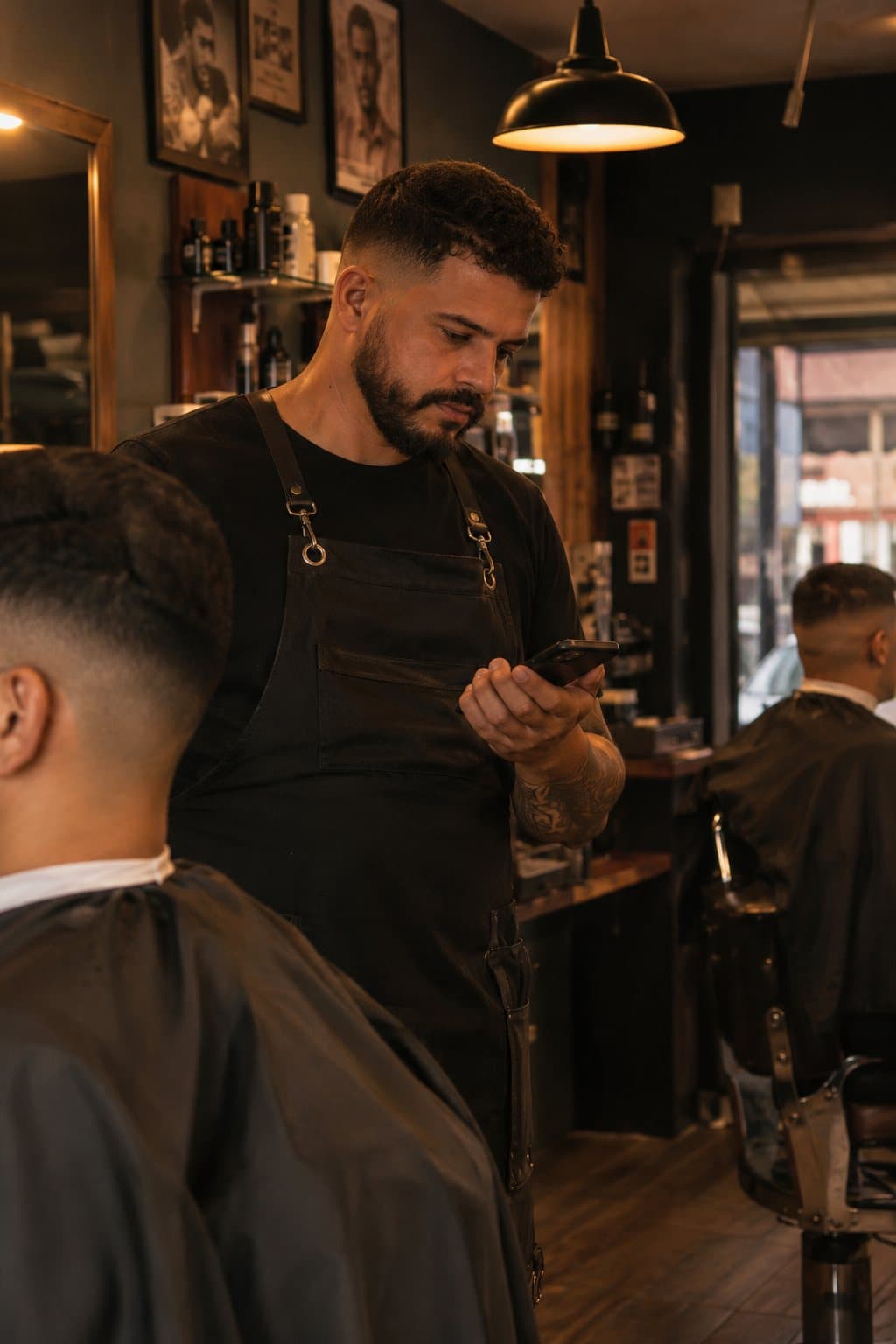 Barbeiro conferindo o celular entre um cliente e outro